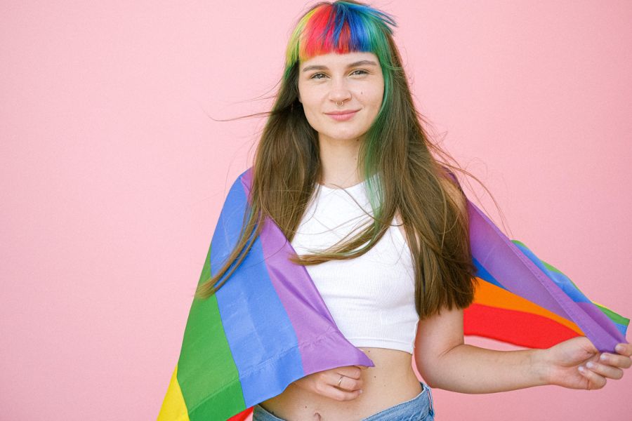 Woman with rainbow hair holding a pride flag